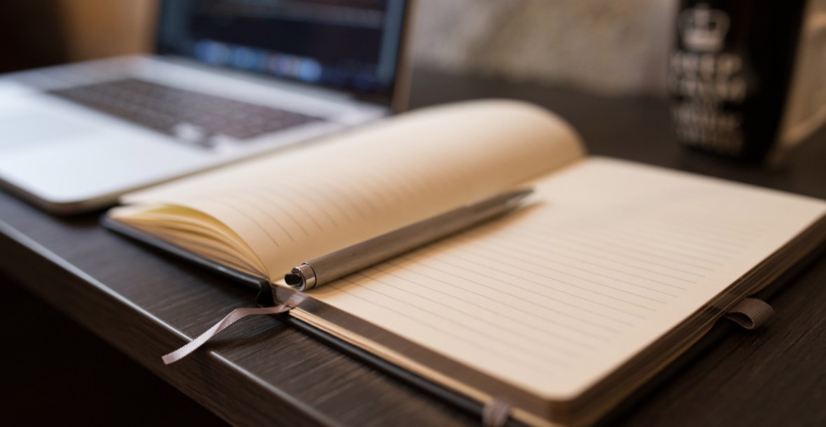 A photo of a notebook, pen and laptop